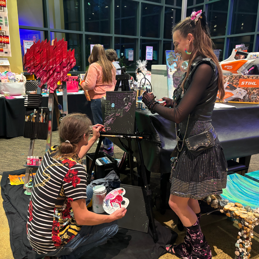 Candid of 2 live painters painting an 80s themed painting during the FSC 2024 Fall Gala & Auction.